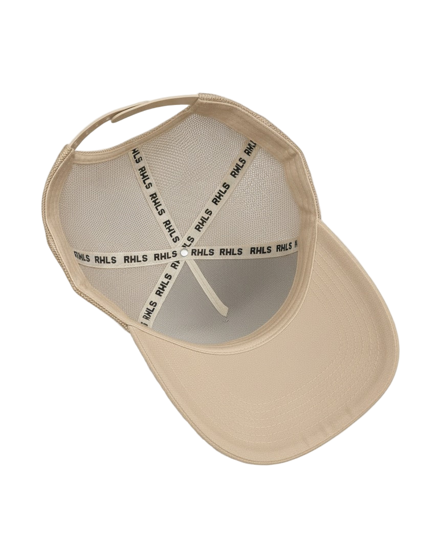 Interior look at the RWLS 121, Beige cream color snapback trucker hat with mesh side panels. Black RWLS logo branding on the inseam tape. Dual snap strap. rebelliouswealth.com
