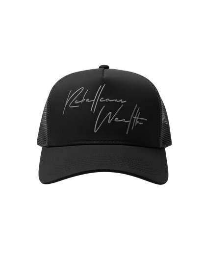 Front view of the Black Rebellious Wealth trucker snapback hat with a gray "Rebellious Wealth" signature on the front panel. Mesh side panels and dual snapback strap. rebelliouswealth.com