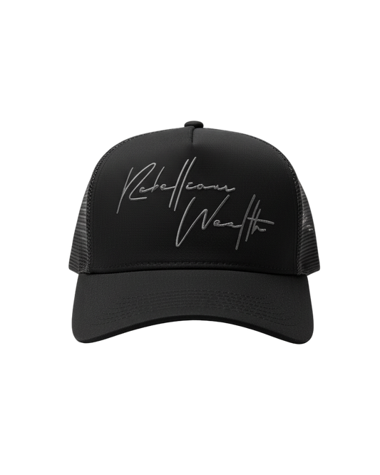 Front view of the Black Rebellious Wealth trucker snapback hat with a gray "Rebellious Wealth" signature on the front panel. Mesh side panels and dual snapback strap. rebelliouswealth.com