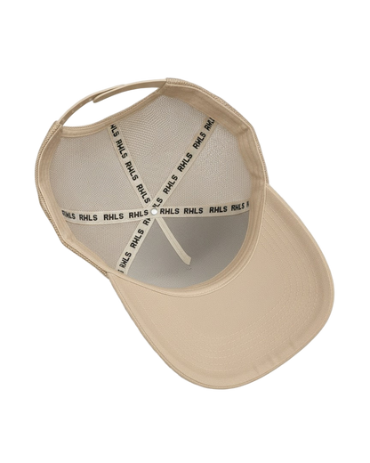 Interior look at the RWLS creamy beige  color snapback trucker hat with mesh side panels. Black RWLS logo branding on the inseam tape. Dual snap strap. rebelliouswealth.com