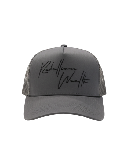 Stone Gray Rebellious Wealth trucker hat with a black "Rebellious Wealth signature on the front panel. Mesh side panels and dual snapback strap. rebelliouswealth.com